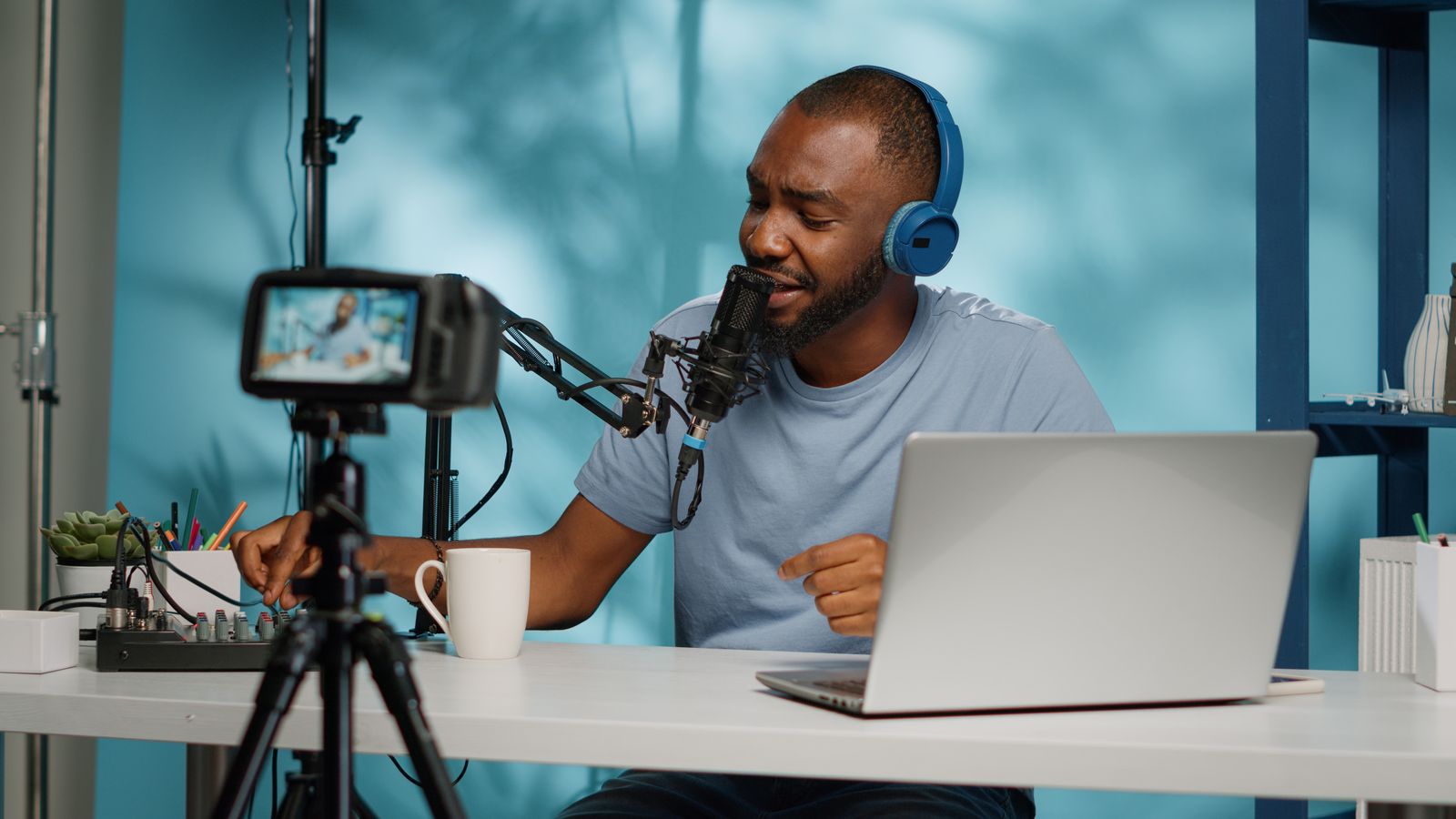 A creator recording a podcast at a home desk, with a microphone, headphones and a laptop.